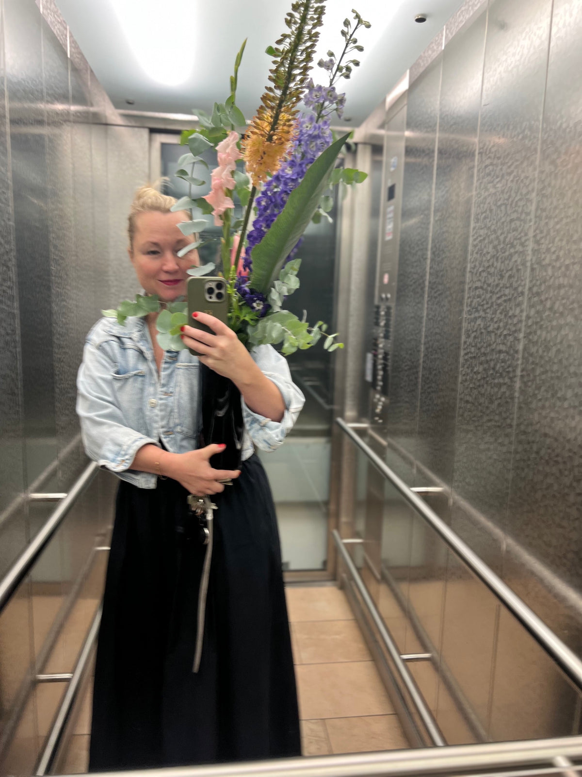 Kirsten mit großem Blumenstrauß im Aufzug – Rosa & Grün Concept Store München