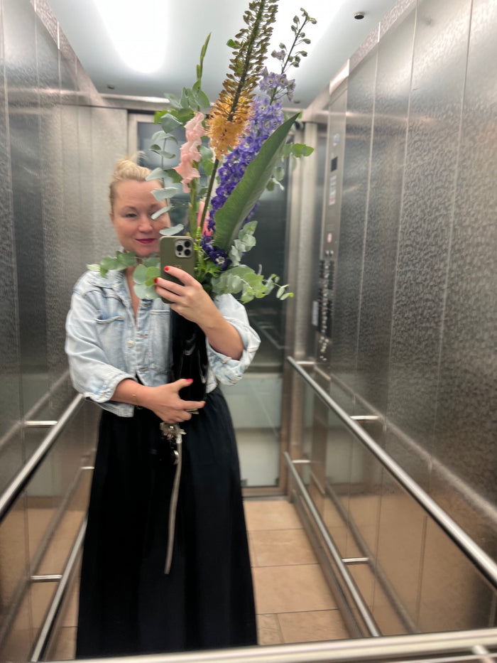 Kirsten mit großem Blumenstrauß im Aufzug – Rosa & Grün Concept Store München